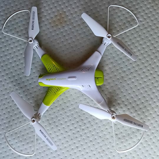 White and green quadcopter drone with four propellers and protective guards