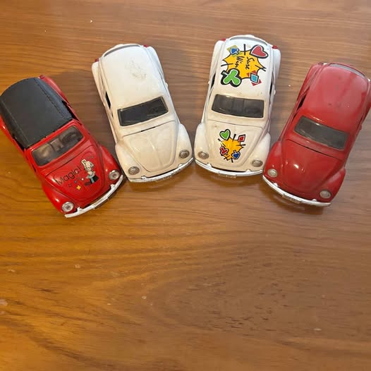 Set of four diecast Volkswagen Beetle cars in red and white, detailed decals