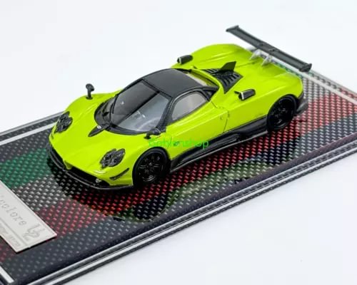 Green racing sports model diecast car on black track section, front 3/4 view