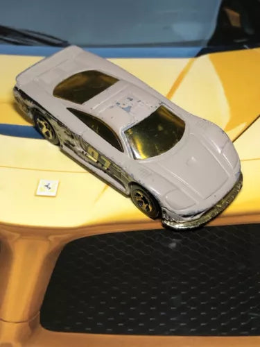 Light beige diecast toy race car with dark camo stripes, black wheels