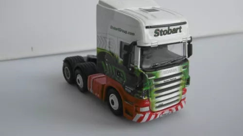 Diecast model truck with white cab, green and orange front, detailed grille and cab mirrors.