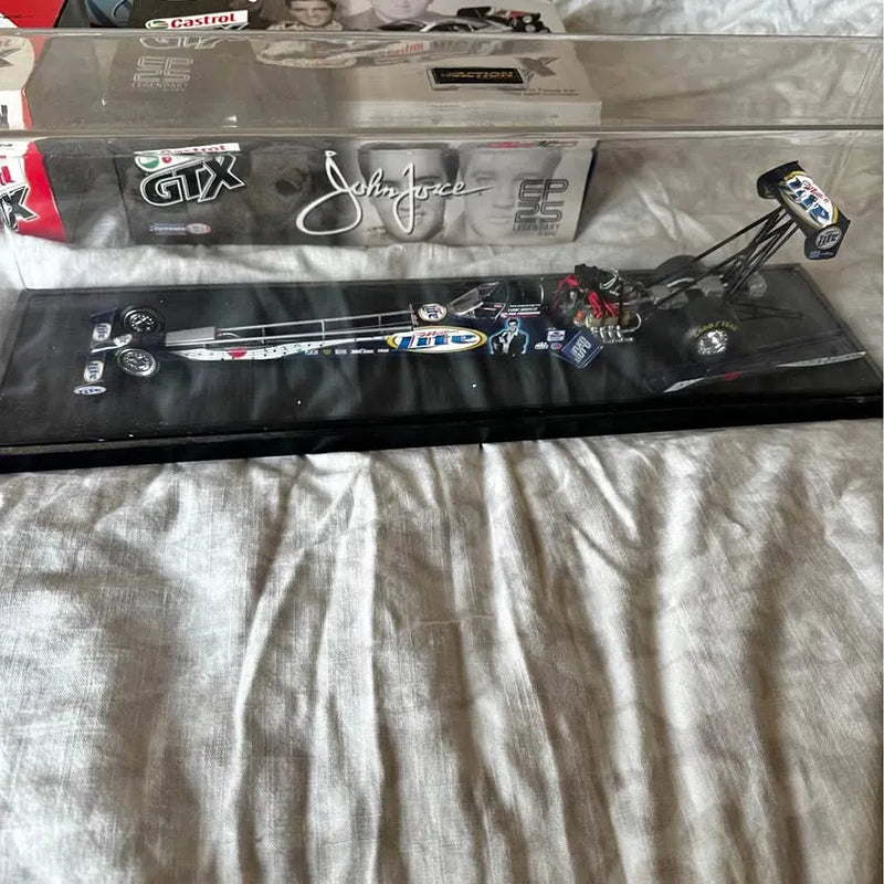 John Force 1:24 diecast dragster model with blue graphics, shown in display box