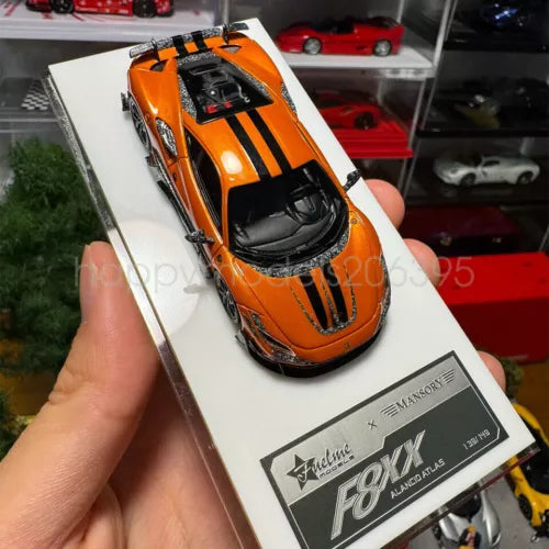 Orange and black racing sports diecast car model with black hood stripes, hand-held view