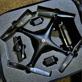 Folded black drone in foam-lined hard case with controller and charging cables