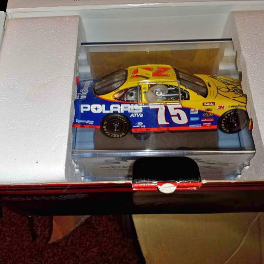 Yellow and blue diecast race car with #75, front-left view in display case