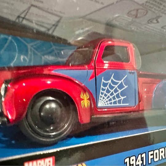 Red diecast pickup truck with blue web graphic and flame side emblem