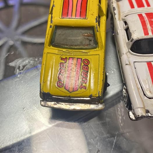 Yellow diecast toy car, front close-up with grille details