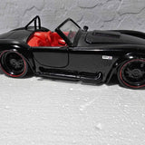 Black diecast sports car model with red interior, side view, 427 emblem on door