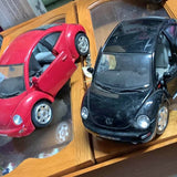 Diecast Volkswagen Beetle toy cars, black and red, front views in display tray