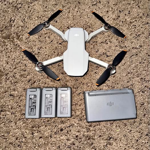 Foldable white drone with four propellers, three gray batteries, and a gray case