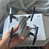 White quadcopter drone with four propellers, D20 HD model, held in hand.