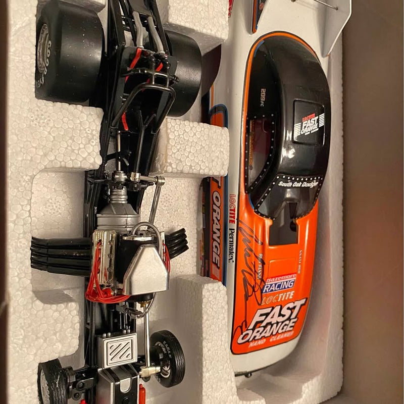 Diecast race car model in orange and white with black wheels in retail box