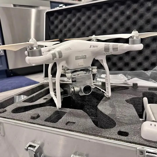 White quadcopter drone with four rotors in hard carrying case, front view