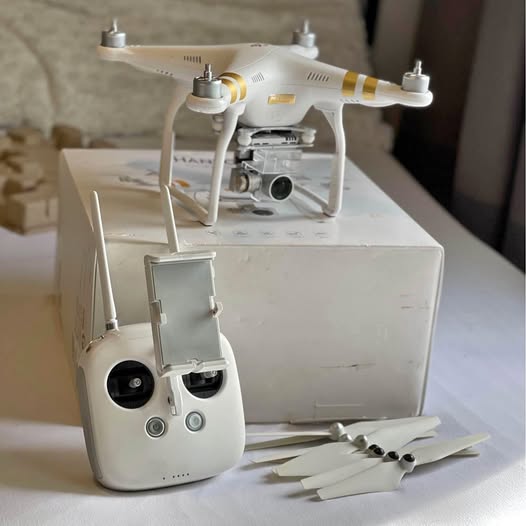 White quadcopter drone with four propellers and handheld remote controller