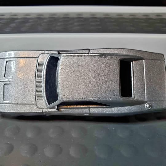 Metal diecast toy car with black window insert, side view, gray finish