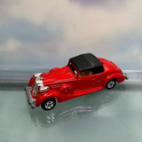 Red diecast coupe model car with black roof and chrome details, side view