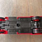 Diecast car chassis with black body and red wheel components, rear and underside view