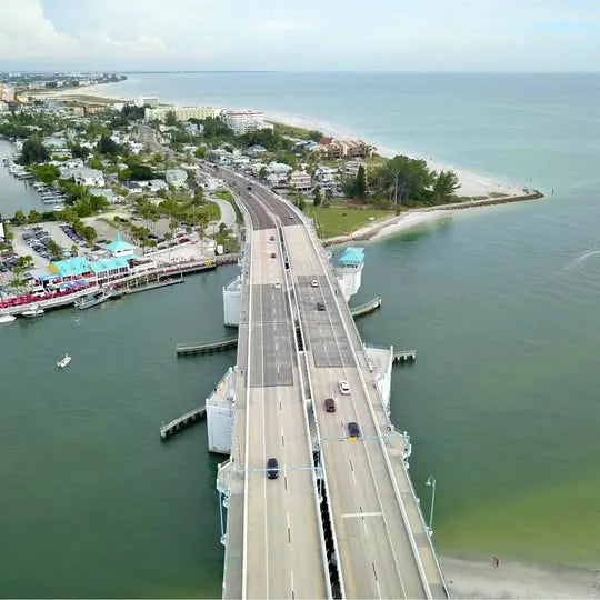 Aerial drone photograph of a bridge over water with boats and roads