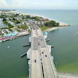 Aerial drone photograph of a bridge over water with boats and roads