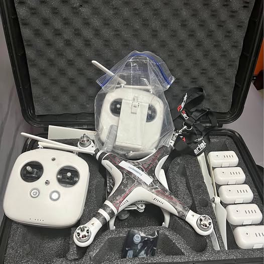 White quadcopter drone with controller and spare batteries in protective case