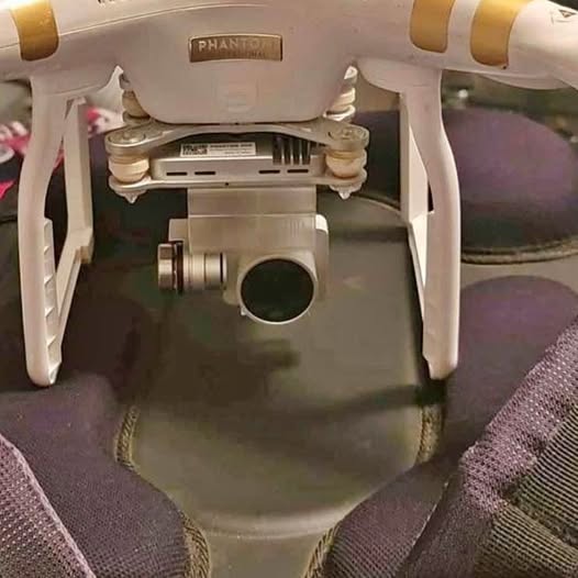 Compact drone with four legs and front camera sensor, light gray body