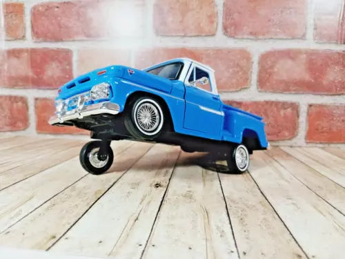 Blue diecast lowrider pickup truck model with detailed wheels and lowered stance