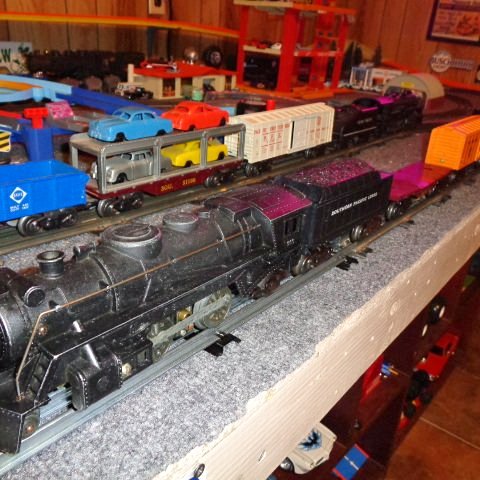 Black diecast steam locomotive with connected freight rail cars on tracks