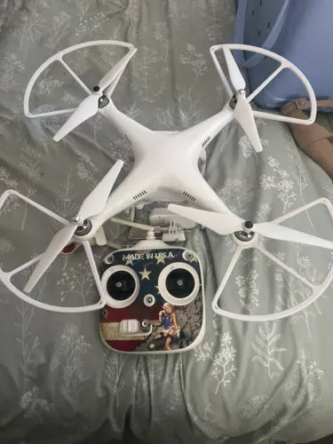White DJI quadcopter drone with four propellers; open battery compartment visible