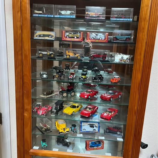 Diecast car display collection in glass cabinet with many model cars