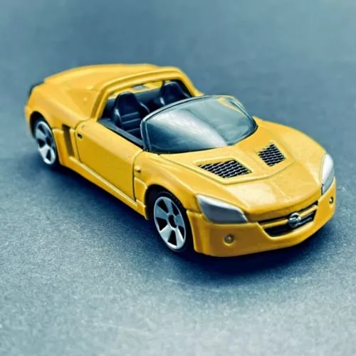 Metallic yellow diecast sports car model with black hood vents and silver front grille