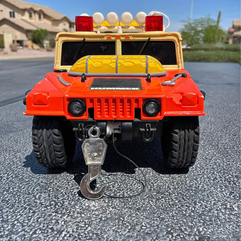 Diecast toy truck, orange-red front with grille, headlights, and metal winch hook