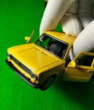 Yellow diecast sedan model car, front three-quarter view with open hood
