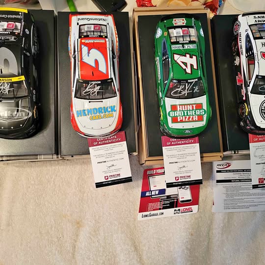 Boxed diecast race cars, one red and one green, with driver signatures and logos