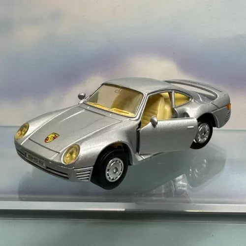 Silver diecast toy sports car with yellow interior, front 3/4 view