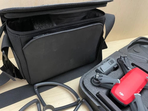 Red camera drone with gray controller in black zip carrying case