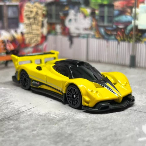 Yellow diecast model sports car with black hood detail, front 3/4 view