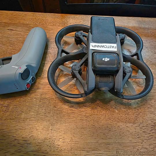 DJI drone with front controller and propellers, gray body