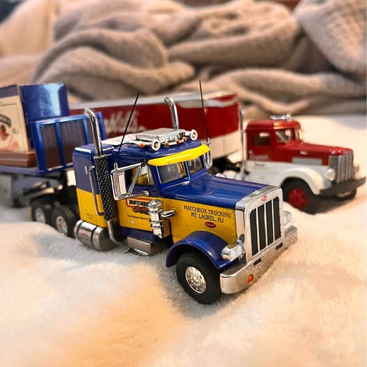 Blue diecast tractor truck with yellow cab and attached trailer, front 3/4 view