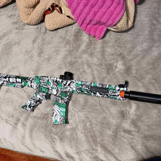 Kids RC drone with green camo body, black arms and orange front nose