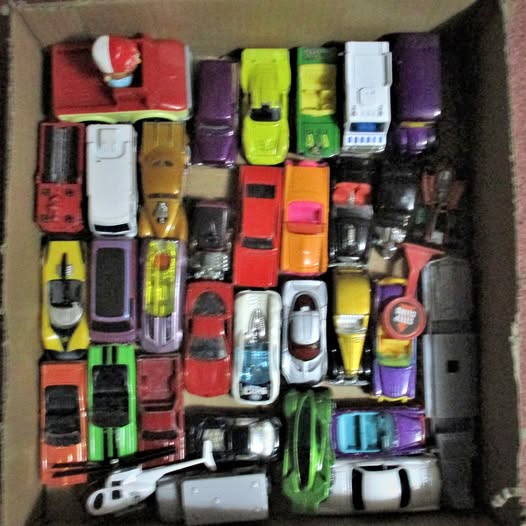 Assorted 1/64 diecast cars in an open box, mixed colors and details