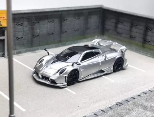 1:64 silver sports model diecast car with black wheels, inside a display bay