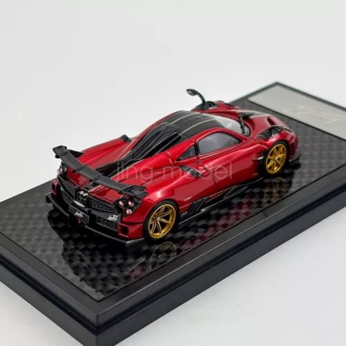 Red diecast sports car model with rear spoiler on black display base