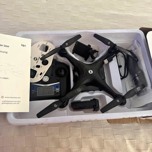 Folded quadcopter drone with remote controller and cables in a retail box