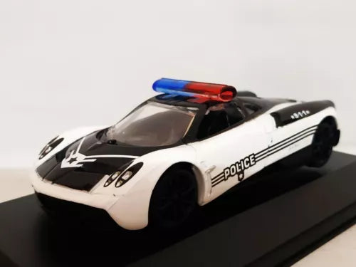 Die-cast police car model, white with black stripes and 'police' graphics, blue/red light bar.