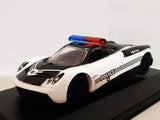 Die-cast police car model, white with black stripes and 'police' graphics, blue/red light bar.