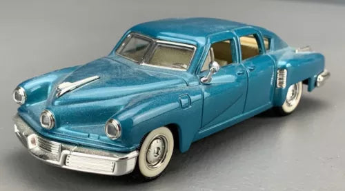 Blue diecast classic car model in front three-quarter view, chrome grille and bumper