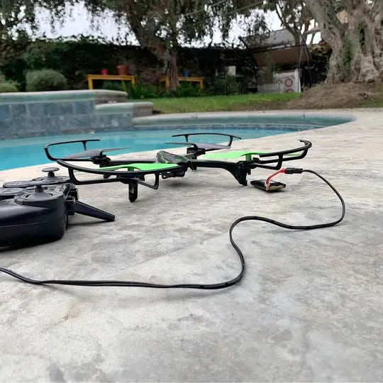 Used quadcopter drone with green frame, landing gear, and connected controller