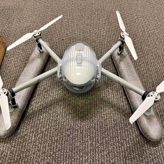 Quadcopter drone with four white propellers and compact camera body