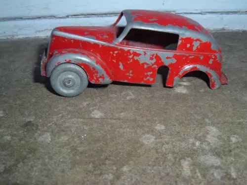Red 1:43 diecast pre-war saloon car body with chipped paint, missing parts.