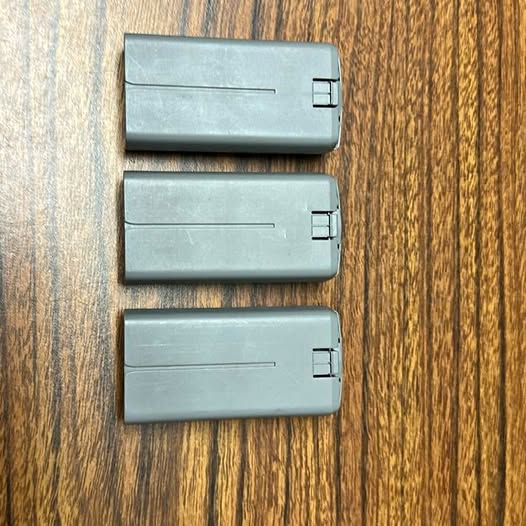 Three gray rectangular drone battery packs with two-pin connector ends